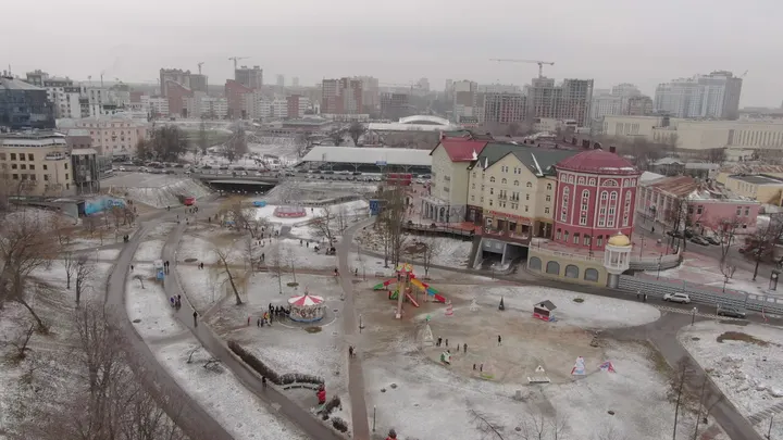 Зимний парк с аттракционами и городской застройкой Рязани